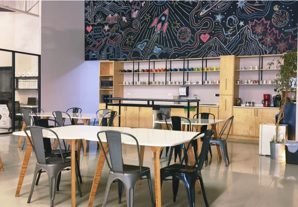 Área común del coworking, con el mural sobre la barra de café